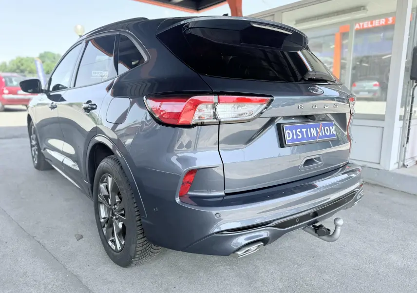 Vue 3/4 arrière droite du Ford Kuga 2023 bleu azur avec attelage rétractable et double sortie d'échappement ST-Line.