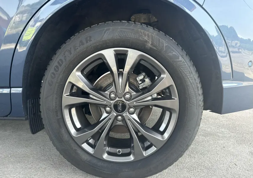 Gros plan sur la roue avant droite du Ford Kuga bleu azur, avec jante alliage 18 pouces finition ST-Line.