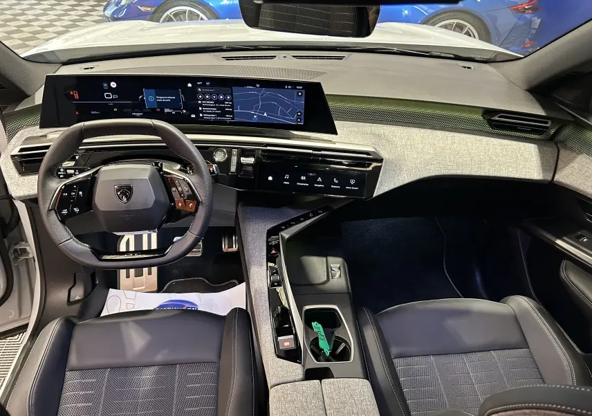 Vue intérieure avant du Peugeot 5008 Hybrid blanc 2025, tableau de bord numérique large et volant compact multifonction.