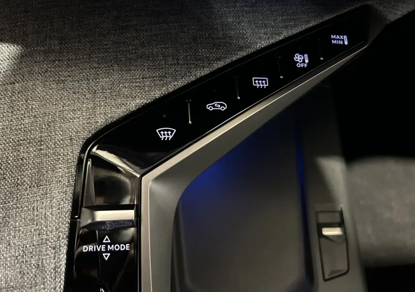 Gros plan sur la console centrale noire avec commandes tactiles du mode de conduite et climatisation du Peugeot 5008 blanc.