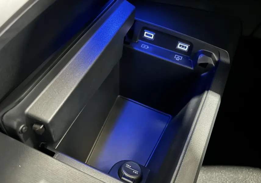 Gros plan sur la console centrale noire avec ports USB et prise 12V du Peugeot 5008 Hybrid blanc.