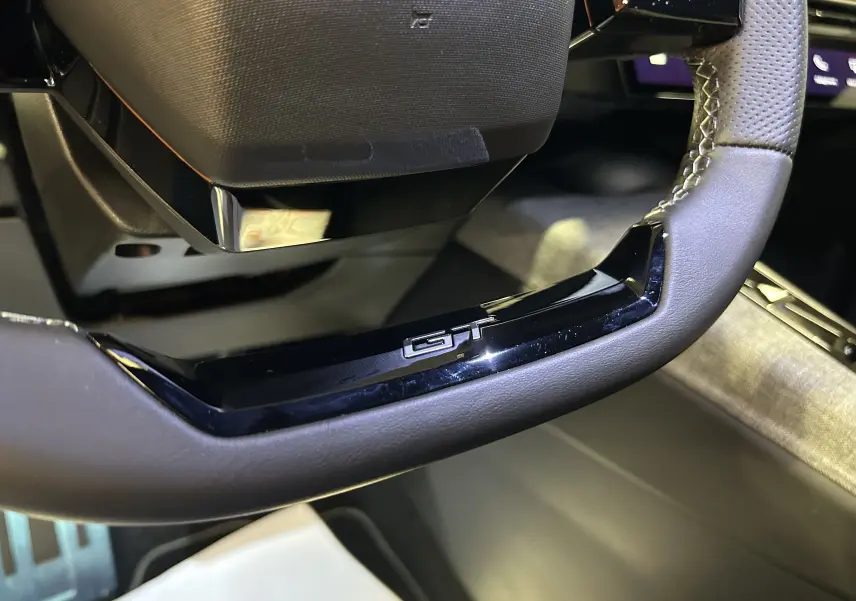 Gros plan sur le volant noir avec logo GT du Peugeot 5008 Hybrid 145ch, intérieur moderne et finition soignée.