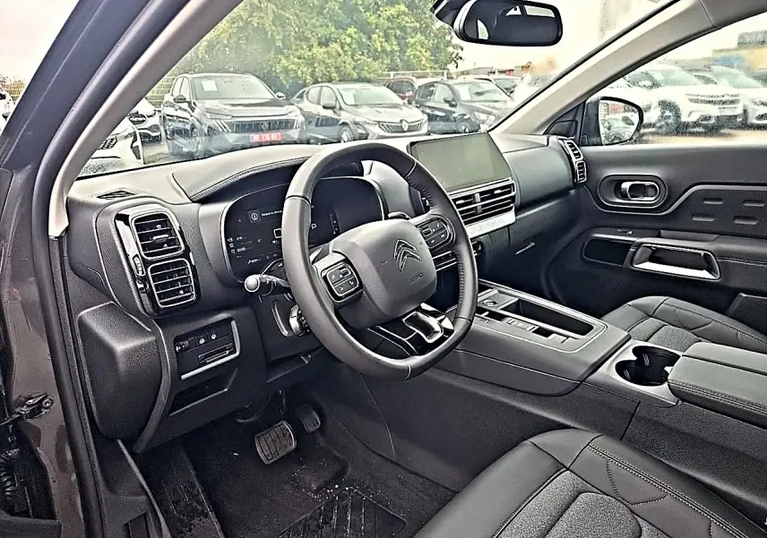 Intérieur avant du Citroën C5 Aircross gris 2025, vue côté conducteur, volant cuir multifonction et écran tactile central.