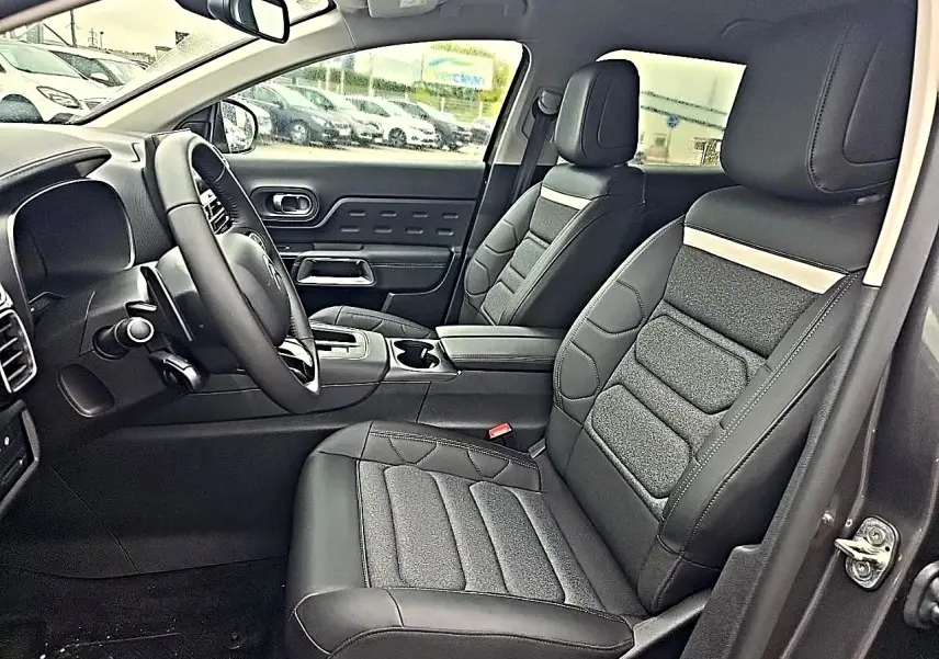 Vue intérieure côté conducteur du Citroën C5 Aircross gris 2025 avec sièges avant en cuir noir et console centrale.