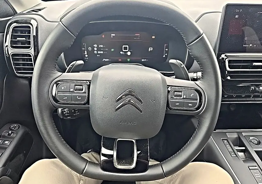 Vue centrée sur le volant cuir noir du Citroën C5 Aircross 2025 avec tableau de bord numérique et écran tactile à droite.