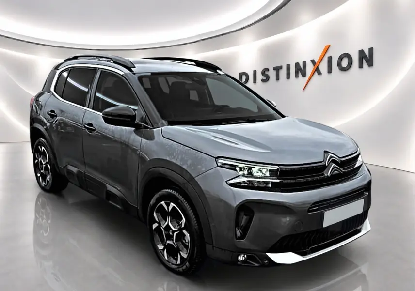 Citroën C5 Aircross gris en 3/4 avant droit, avec barres de toit et jantes alliage distinctives.