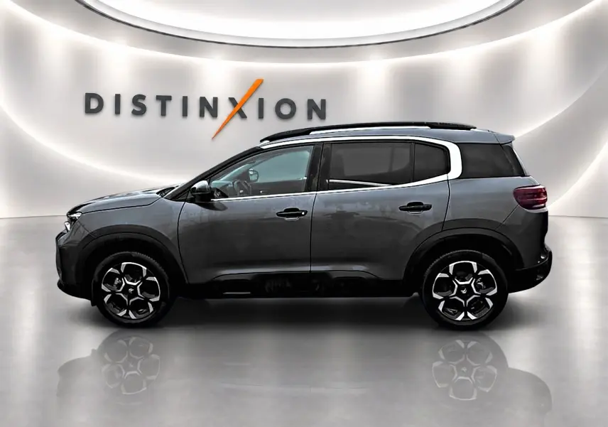 Profil droit du Citroën C5 Aircross gris 2025 avec toit noir et jantes alu distinctives en showroom.