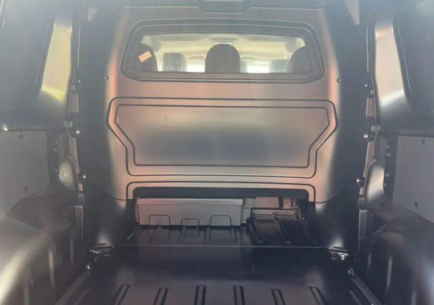 Vue intérieure arrière du Peugeot Expert Fourgon gris platinium, montrant la cloison pleine avec vitre plexiglass et espace de chargement.