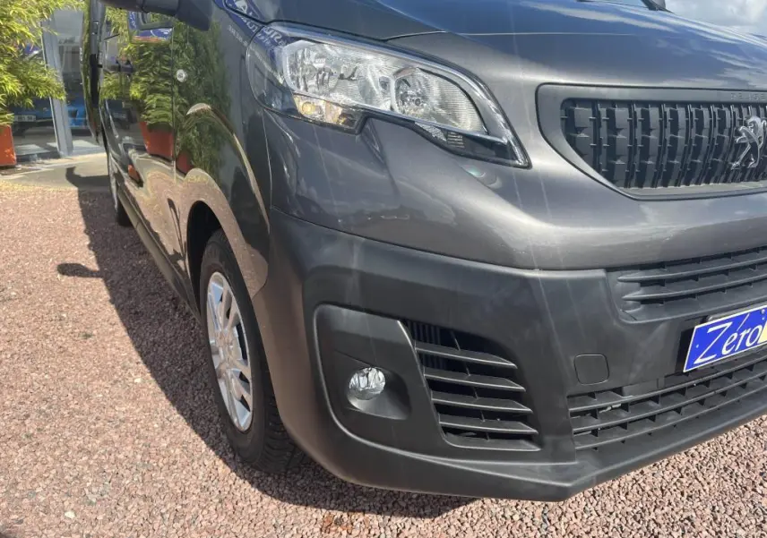 Vue 3/4 avant droit du Peugeot Expert Fourgon gris platinium métal avec projecteurs antibrouillard et calandre noire.