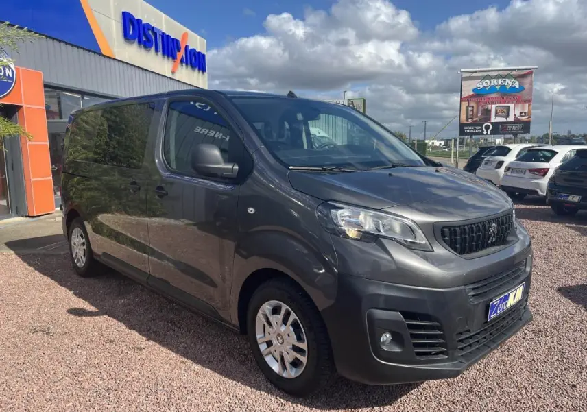 Peugeot Expert Fourgon gris platinium métal en 3/4 avant droit, stationné devant un bâtiment commercial.