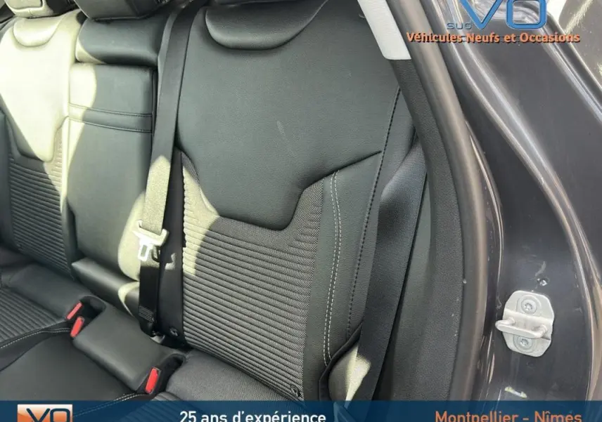 Vue rapprochée du siège arrière droit en cuir noir du Jeep Compass gris 2024 avec ceinture de sécurité visible.