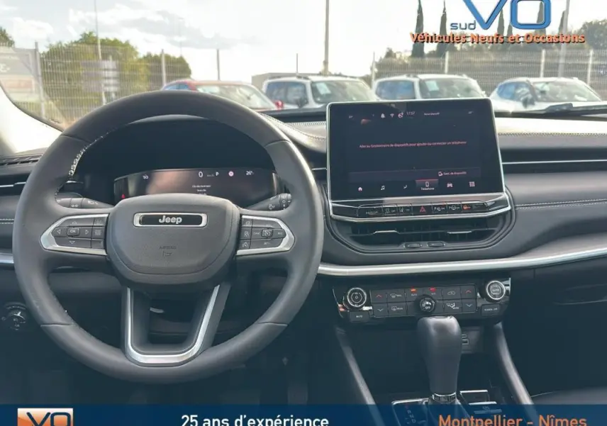 Vue intérieure du tableau de bord et volant du Jeep Compass gris 2024 avec écran tactile et commandes au volant visibles.