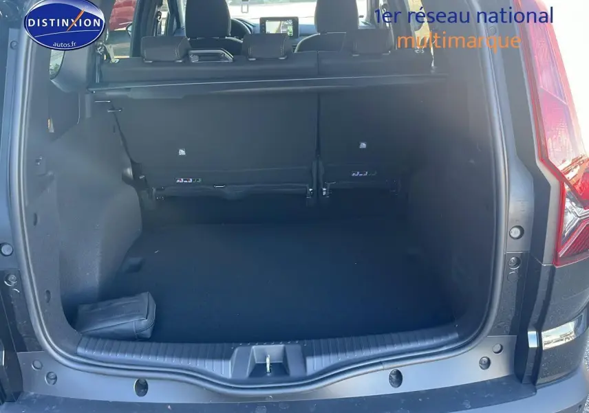 Coffre ouvert vu de l'arrière d'un Dacia Jogger noir nacré 2024 avec banquette arrière et tablette cache-bagages.