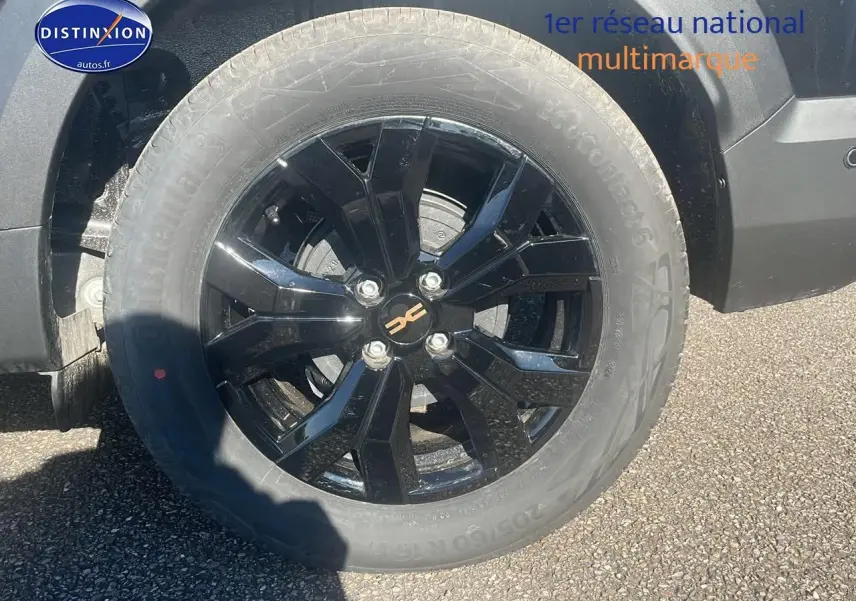 Gros plan sur la jante alu noire brillante côté gauche du Dacia Jogger 1.6 hybrid 140 Extreme noir nacré 2024.