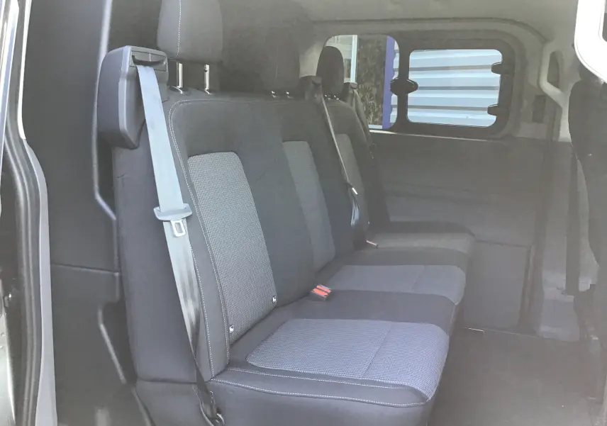 Banquette arrière en tissu gris et noir du Volkswagen Transporter ProCab 2025, vue côté gauche avec ceinture de sécurité visible.