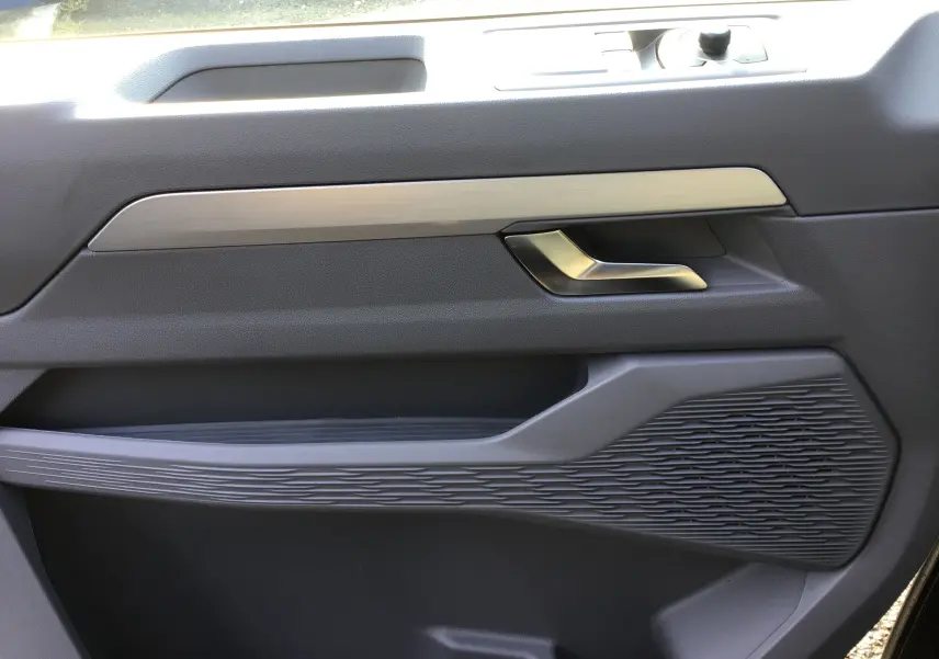 Gros plan sur la garniture intérieure de la porte côté droit du Volkswagen Transporter ProCab gris anthracite, avec poignée métal brossé.