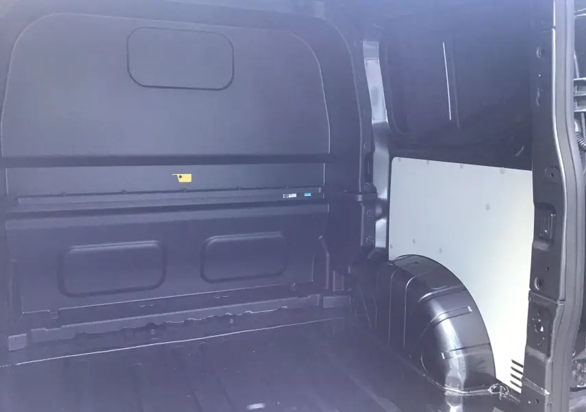 Vue intérieure du compartiment de charge arrière du Volkswagen Transporter ProCab gris anthracite, montrant la cloison et les passages de roue.