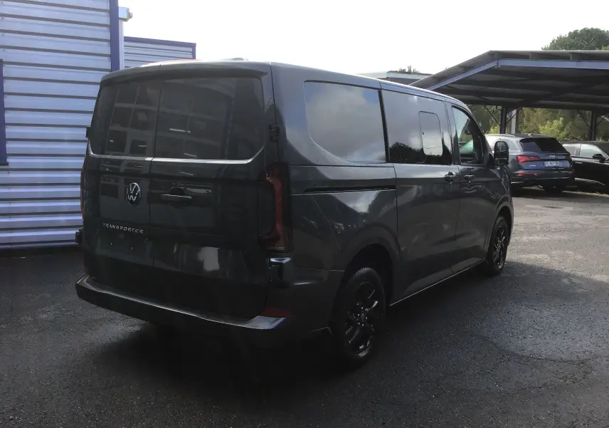 Vue 3/4 arrière droite d'un Volkswagen Transporter ProCab gris anthracite avec jantes alu noires et vitres teintées.