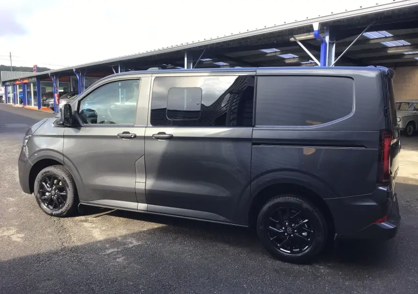 Vue latérale droite d'un Volkswagen Transporter ProCab gris anthracite avec jantes alu noires et vitres latérales teintées.
