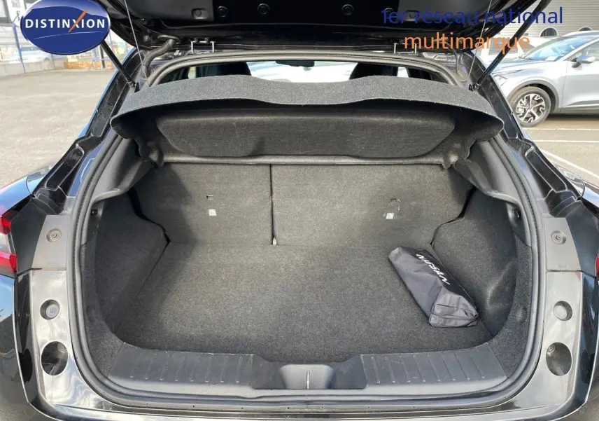 Coffre ouvert d'un Nissan Juke noir métal 2024, montrant un espace de chargement propre avec un sac Nissan à droite.