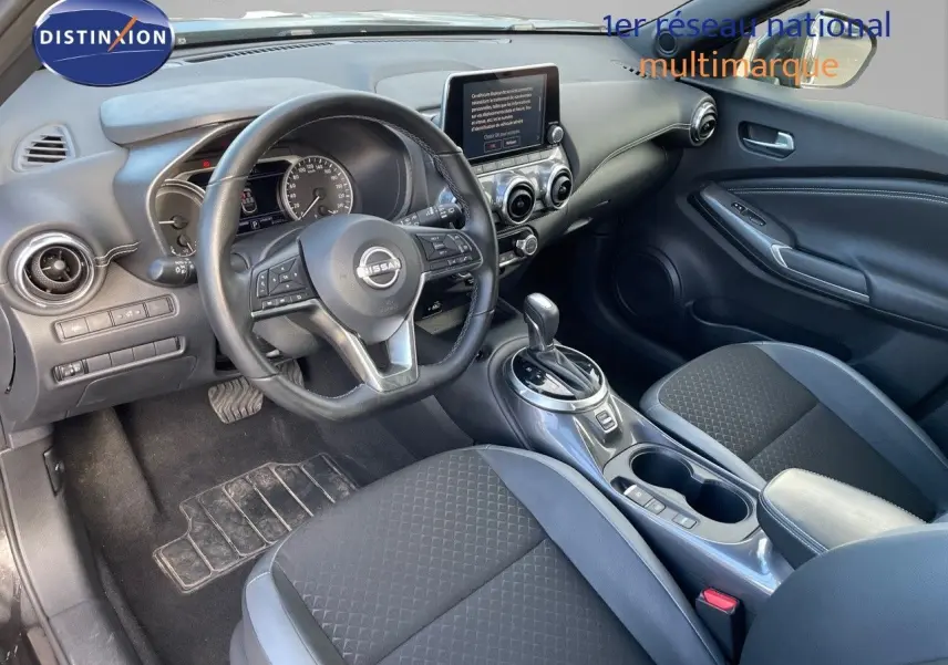 Intérieur du Nissan Juke 2024 noir métal, vue côté conducteur montrant le tableau de bord et la console centrale moderne.