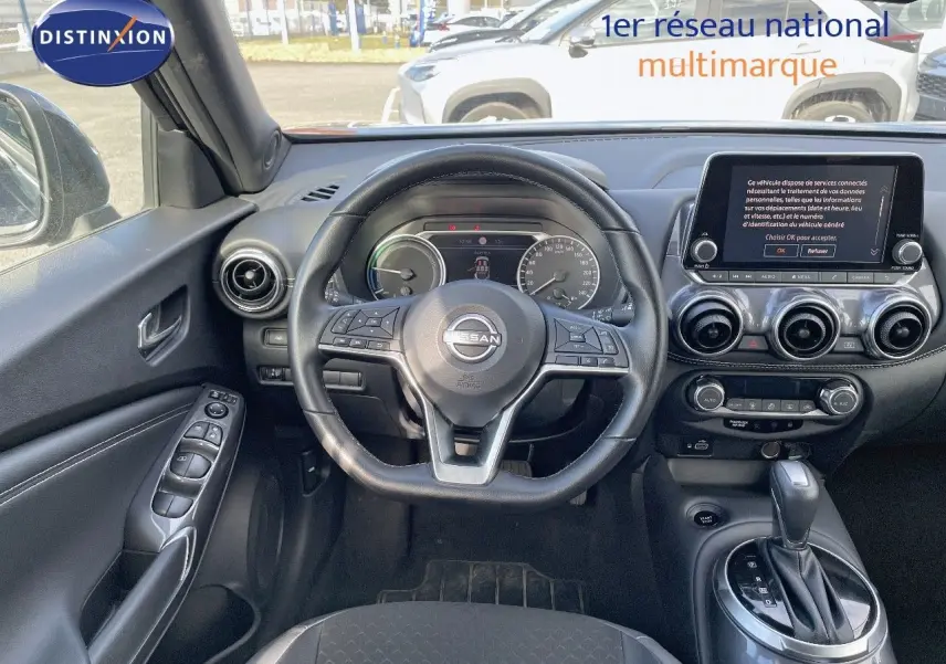 Vue intérieure du tableau de bord et volant noir du Nissan Juke 1.6 HEV 2024 avec écran tactile et boîte automatique.