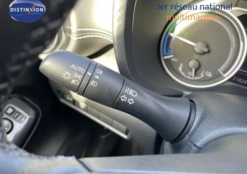 Gros plan sur la commande des phares et clignotants du Nissan Juke 2024 noir métal, avec tableau de bord hybride en arrière-plan.