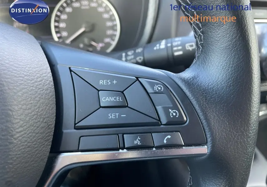 Gros plan sur les commandes de régulateur de vitesse au volant cuir noir du Nissan Juke 2024 hybride.