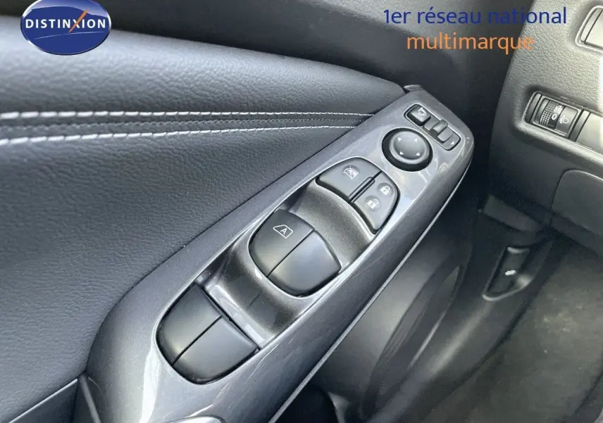 Gros plan sur les commandes de lève-vitres et rétroviseurs côté conducteur du Nissan Juke noir métal 2024.