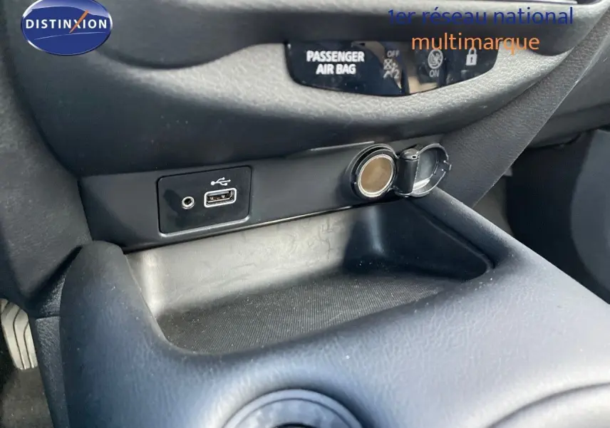 Prise USB et allume-cigare en gros plan sur la console centrale du Nissan Juke noir métal 2024.