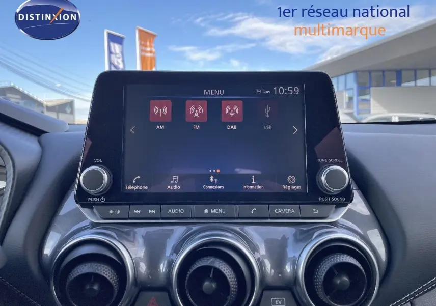 Vue rapprochée de la console centrale du Nissan Juke 2024 noir métal, avec écran tactile et commandes d’aération circulaires.