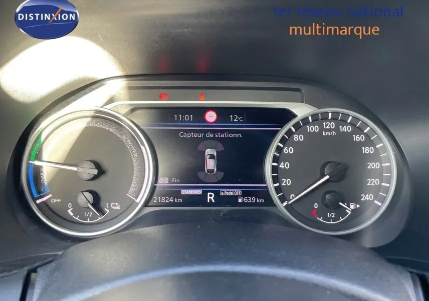 Tableau de bord du Nissan Juke 2024 noir métal, affichant compteurs et écran central avec capteur de stationnement actif.