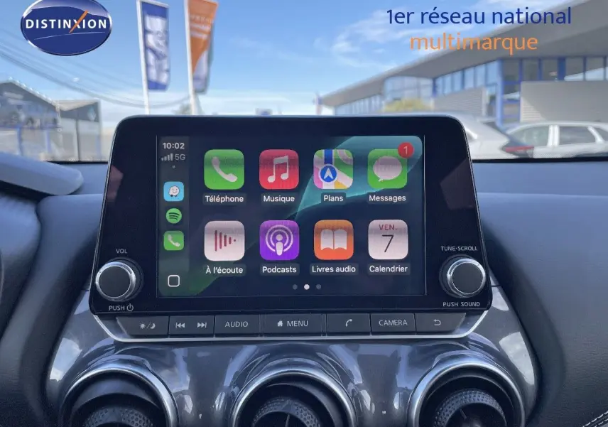 Écran tactile central allumé avec interface Apple CarPlay dans le tableau de bord du Nissan Juke noir métal 2024.