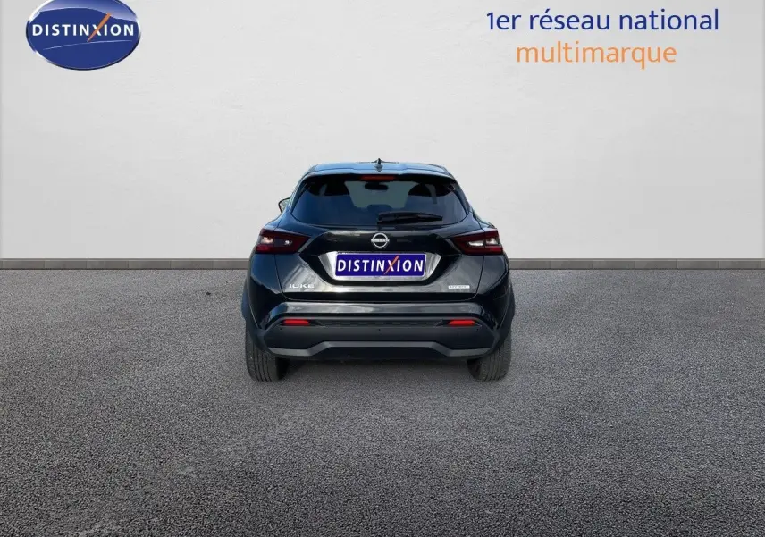 Vue arrière d'un Nissan Juke noir métal 2024, version hybride, garé sur un sol gris devant un mur blanc.