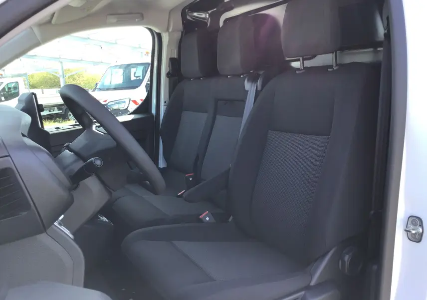 Vue intérieure côté conducteur du Peugeot Expert Fourgon blanc 2025, montrant les sièges noirs et la banquette Moduwork.