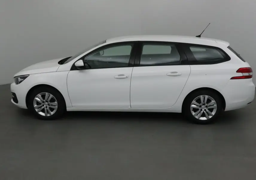 Profil latéral droit d'une Peugeot 308 SW blanche de 2018, break compact avec jantes alliage et antenne sur le toit.