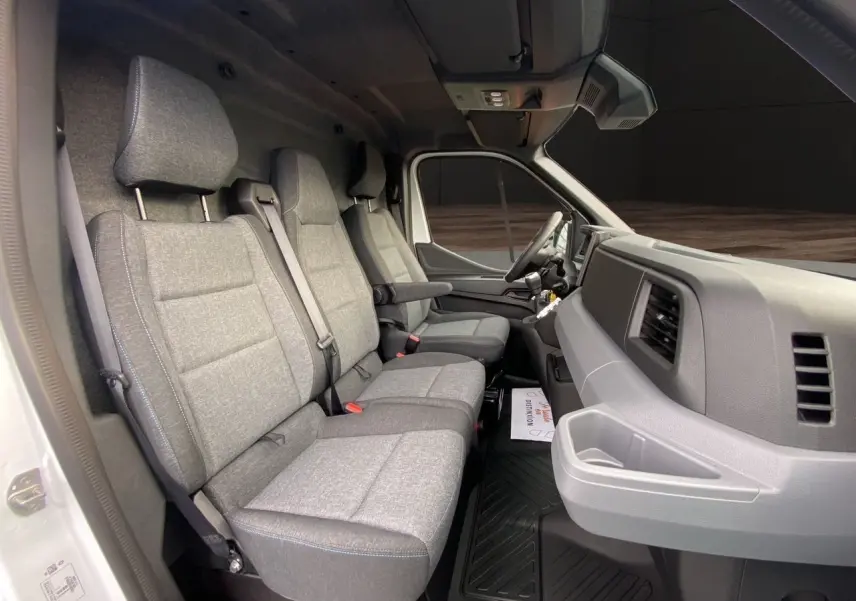 Vue intérieure côté passager du Renault Master blanc 2025, montrant la banquette grise à trois places et le tableau de bord.