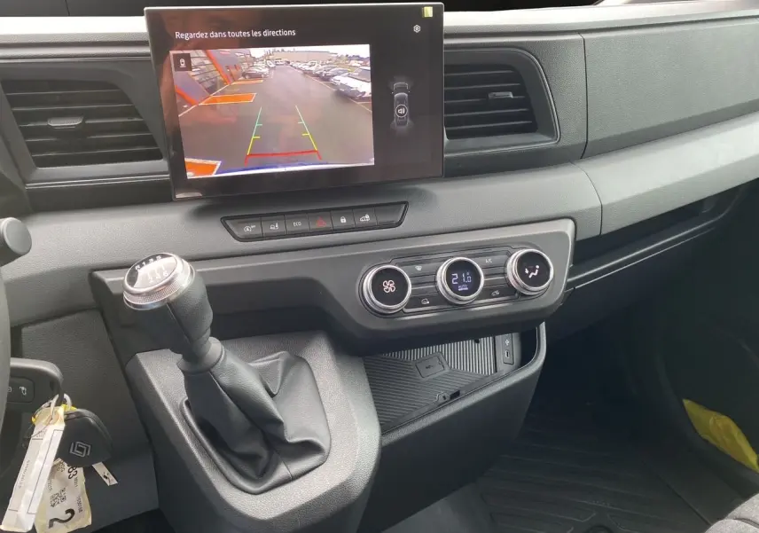Vue intérieure du tableau de bord du Renault Master 2025, avec levier de vitesse manuel et écran de caméra de recul allumé.