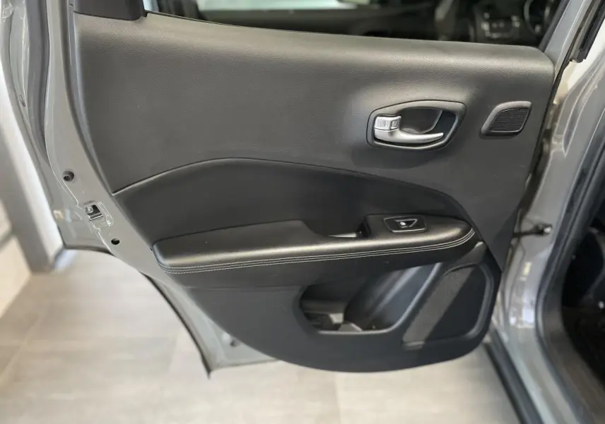 Porte arrière droite ouverte du Jeep Compass gris foncé, montrant la garniture intérieure noire avec commande de vitre.