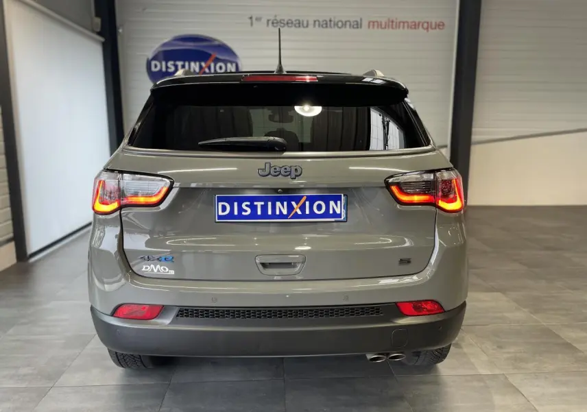 Vue arrière d'un Jeep Compass gris foncé avec feux arrière allumés et double sortie d'échappement visible.