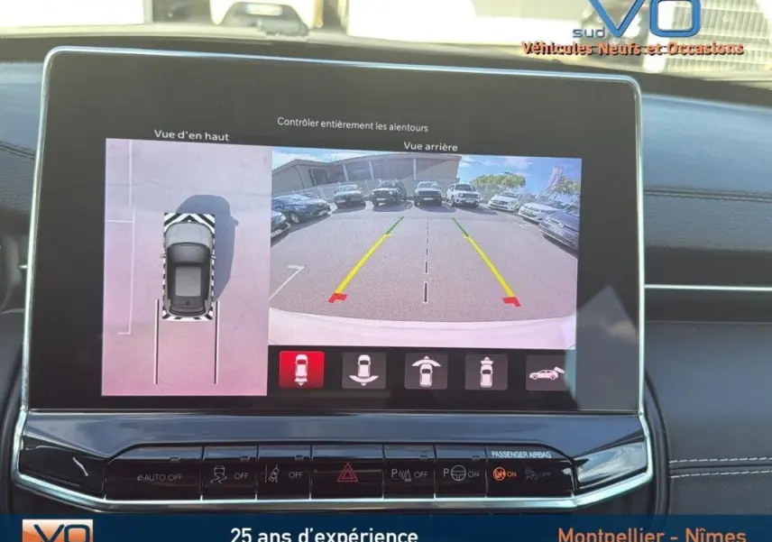 Écran tactile du Jeep Compass blanc 2024 montrant la caméra de recul et la vue en hauteur du stationnement.