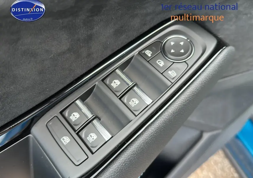 Gros plan sur les commandes des vitres électriques côté conducteur d’un Renault Austral bleu, avec finition intérieure noire.