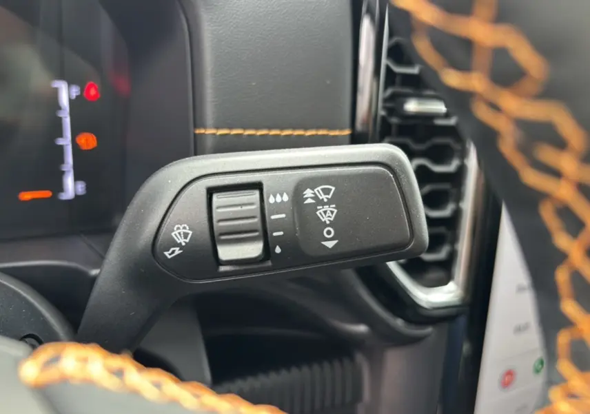 Gros plan sur la commande des essuie-glaces du Ford Ranger Wildtrak 2025, volant cuir noir avec surpiqûres orange.