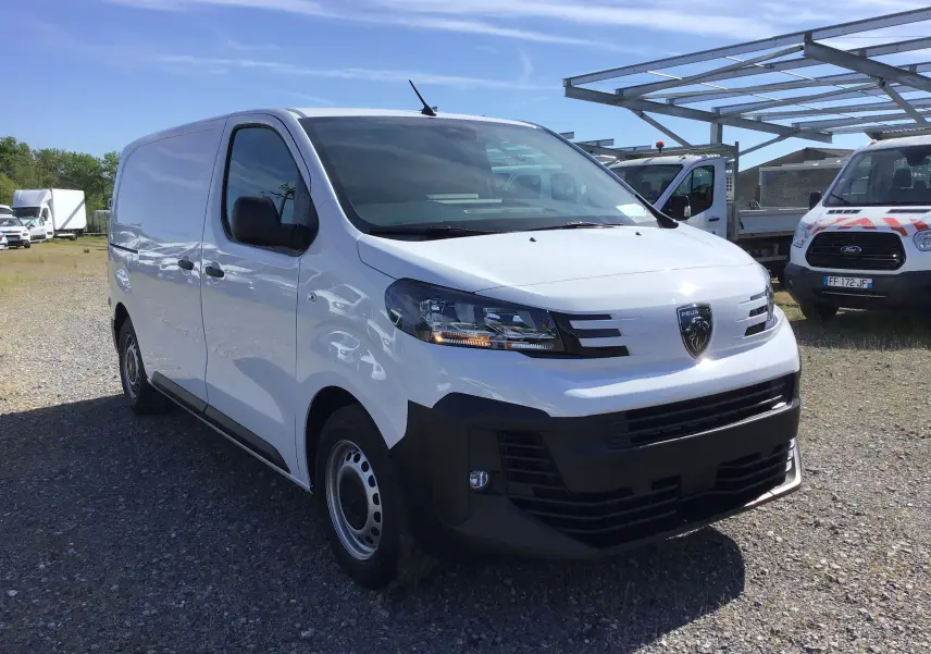 Vue 3/4 avant d'un Peugeot Expert Fourgon blanc 2025 avec calandre noire et feux modernes, stationné en extérieur.