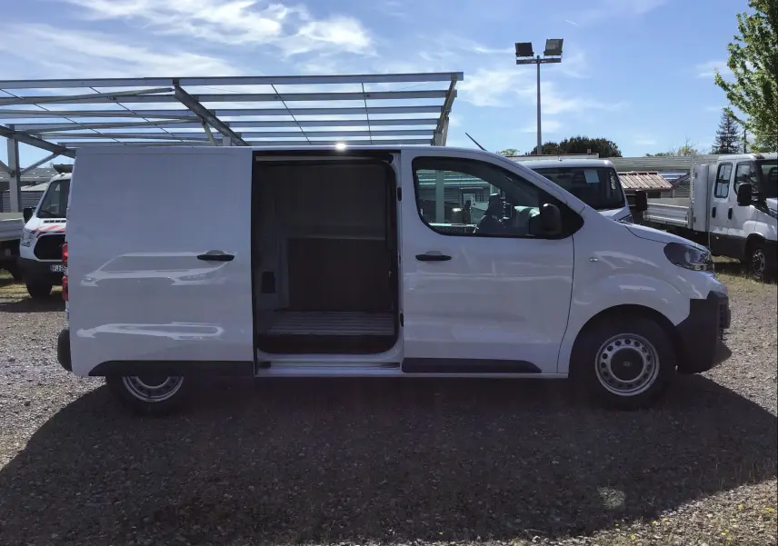 Vue de profil côté droit d'un Peugeot Expert Fourgon blanc 2025 avec porte coulissante ouverte montrant l'espace de chargement.