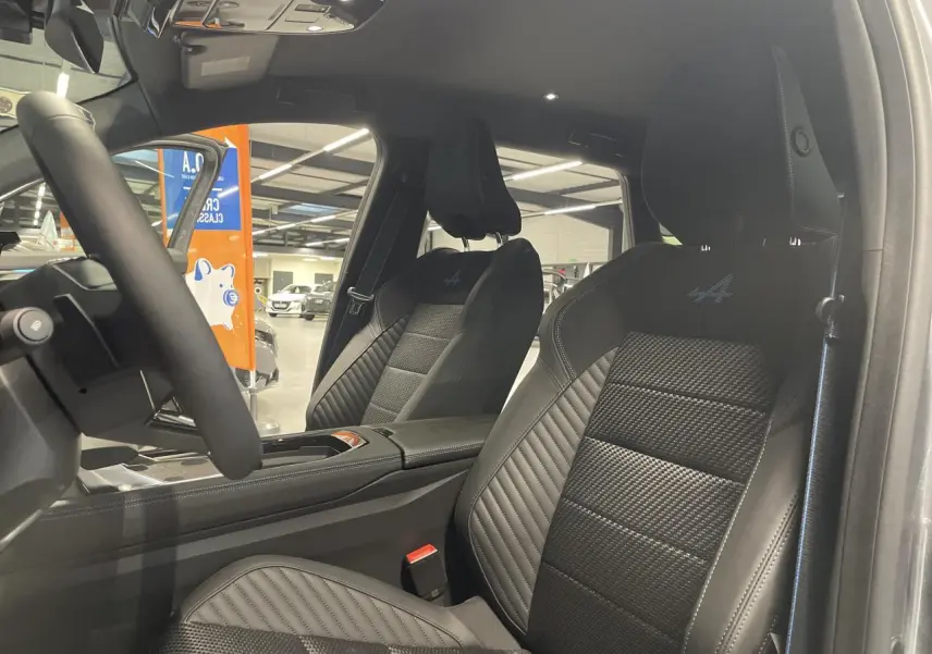 Vue intérieure côté conducteur du Renault Austral Esprit Alpine 2025, sièges noirs avec logo Alpine brodé bleu.