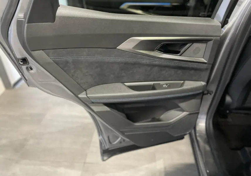 Gros plan sur la porte arrière gauche gris métallisé du Renault Austral avec garniture en Alcantara et surpiqûres bleues.