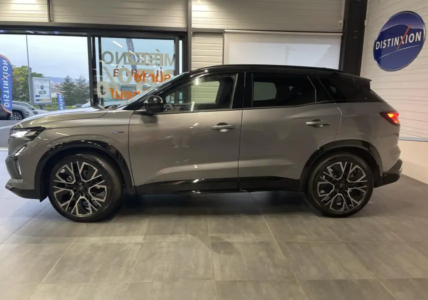 Profil côté gauche du Renault Austral gris métallisé avec toit noir étoilé et jantes alliage noires diamantées.