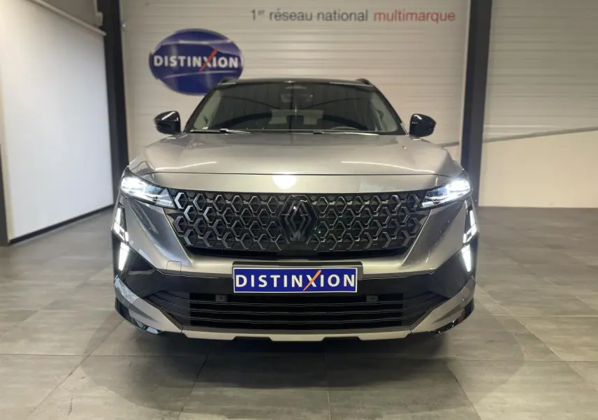 Vue frontale d'un Renault Austral gris métallisé avec calandre noire et feux LED allumés en intérieur showroom.