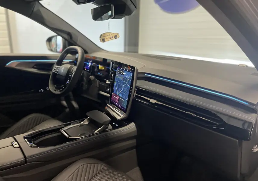 Intérieur Renault Austral 2025 vu côté conducteur, tableau de bord noir avec écran tactile vertical et éclairage bleu fin.